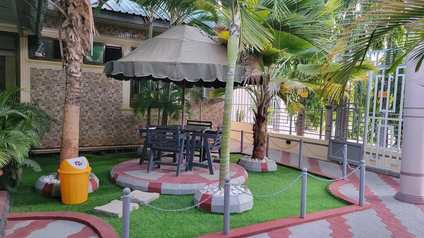 Garden tables under an umbrella surrounded by palms
