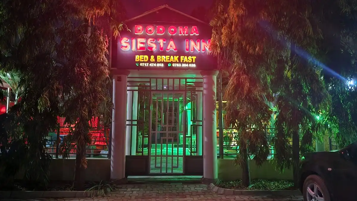 The inn's sign glowing red over the gate at night